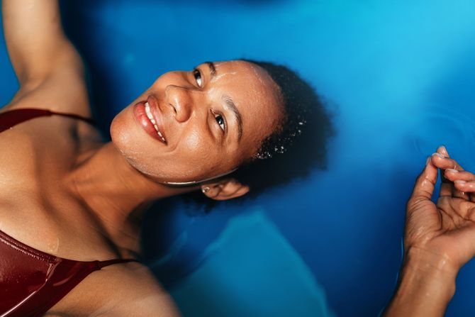 A woman in a red bikini is floating in a blue pool.