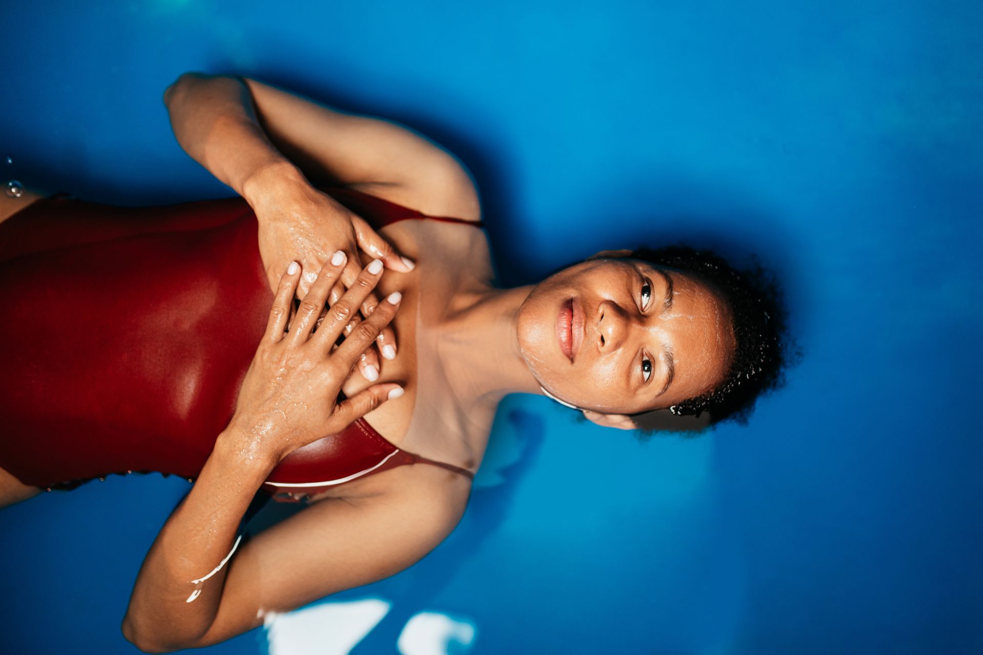 A woman in a red swimsuit is floating in a blue pool.