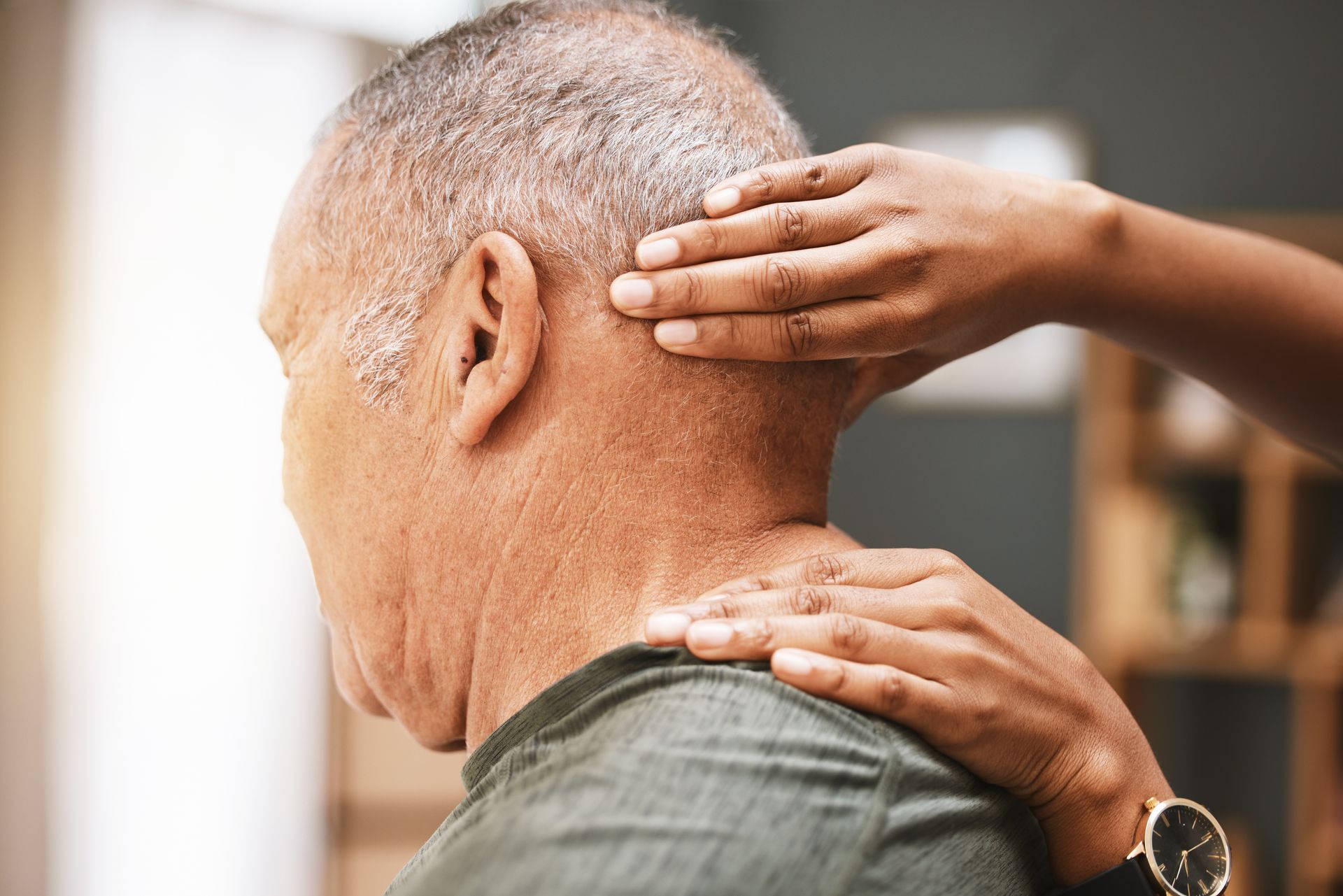 An elderly man is getting a massage from a woman.