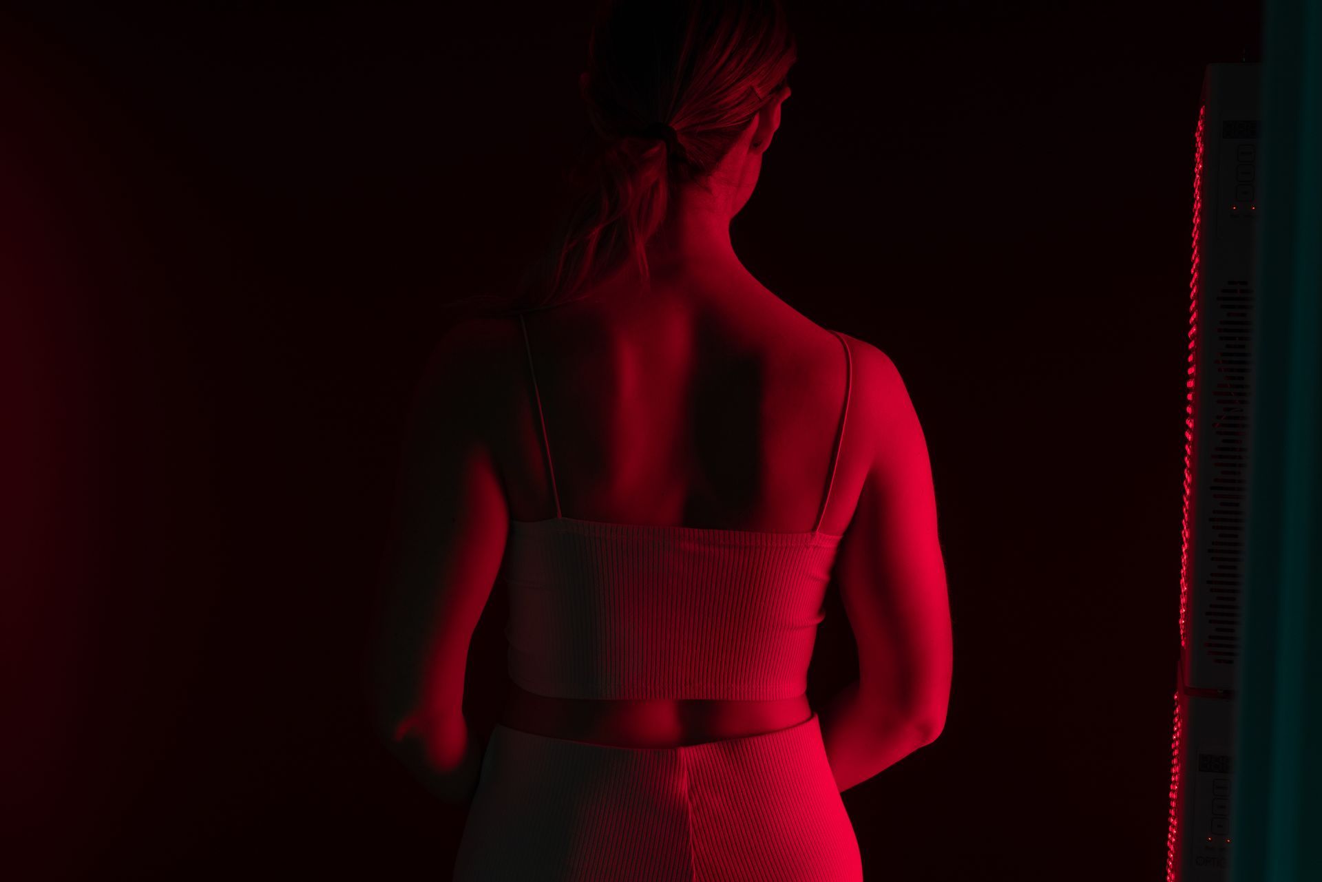 A woman in a white dress is standing in front of a red light.