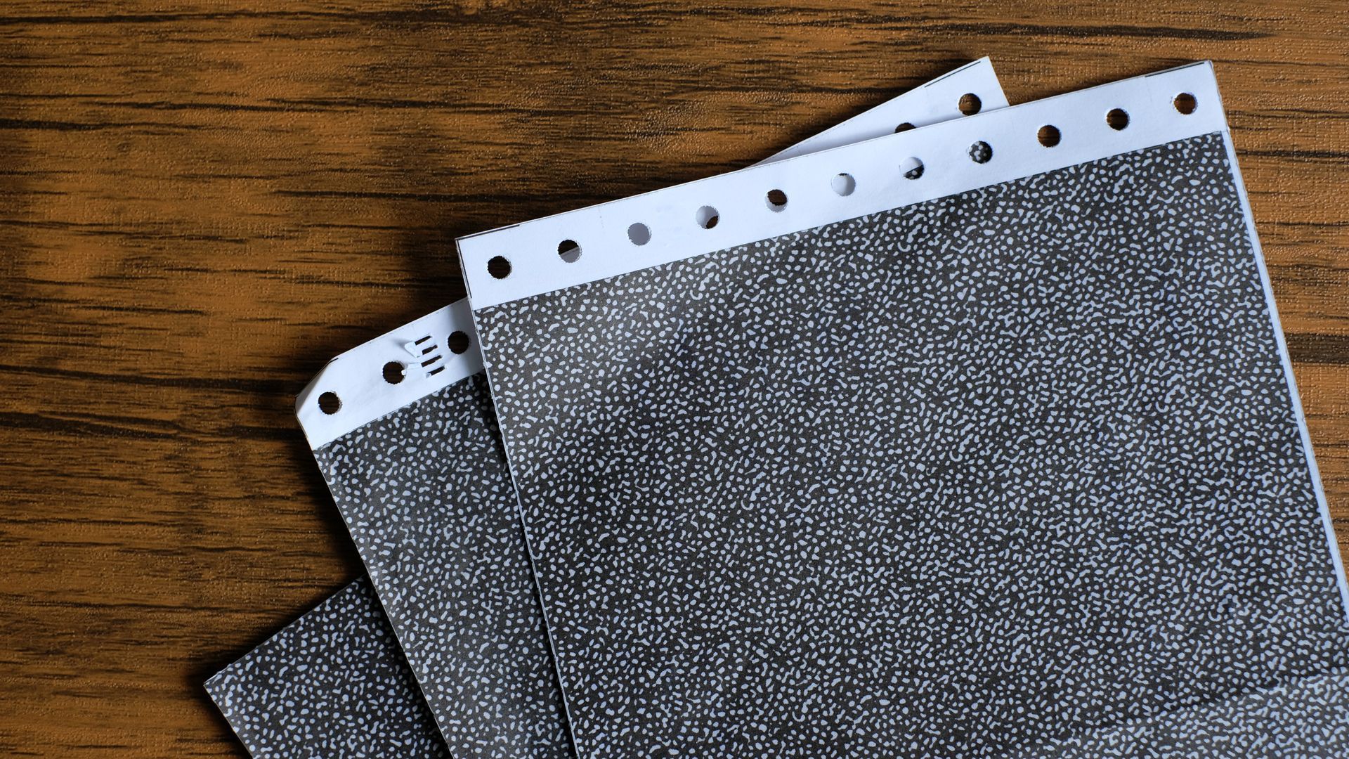 Printed sealed payslips on a wooden surface, each with a row of holes along the top edge.