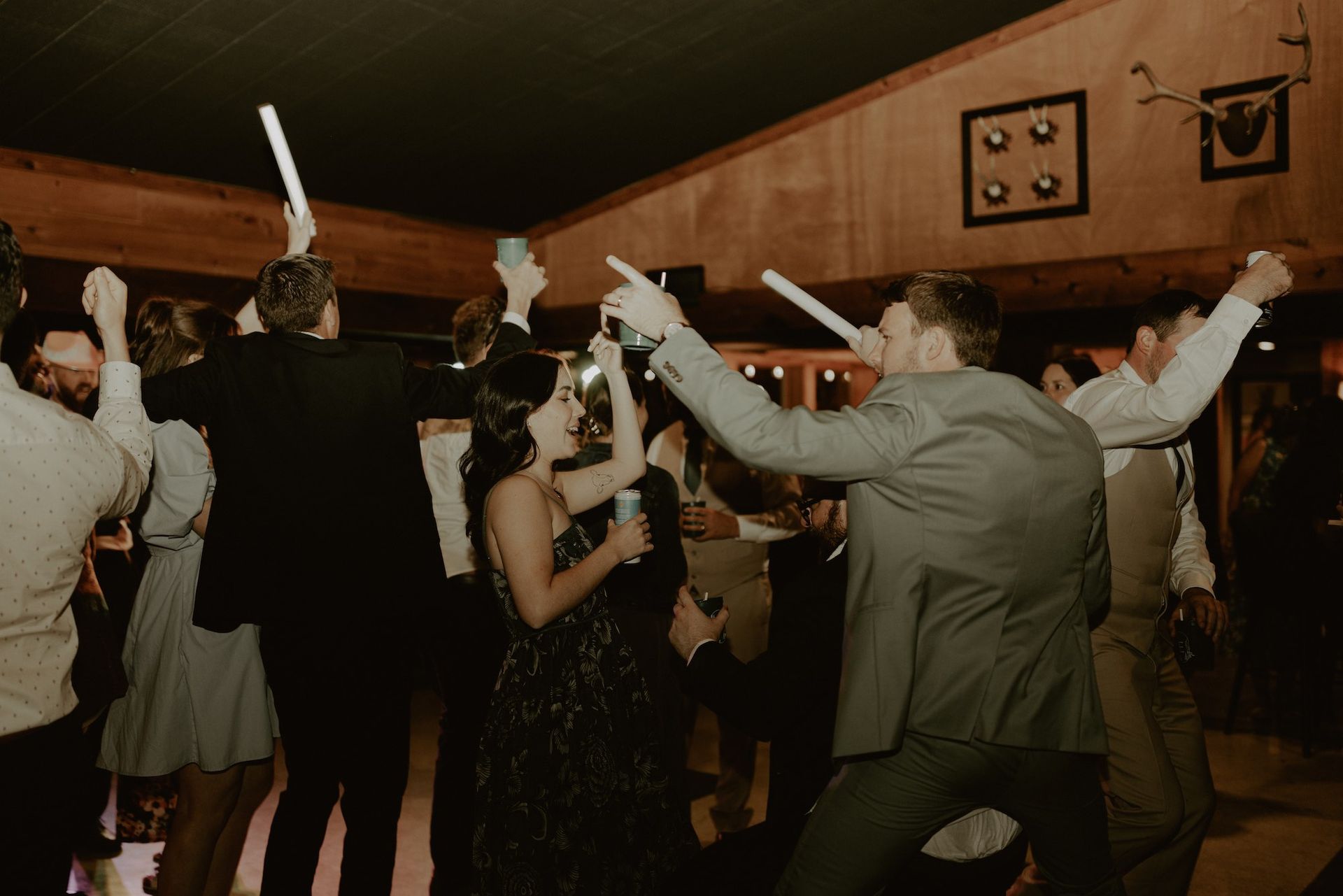 Wedding guests dancing with foam light-up sticks inside the Camp Elsewhere tent with Sound Sensations DJ