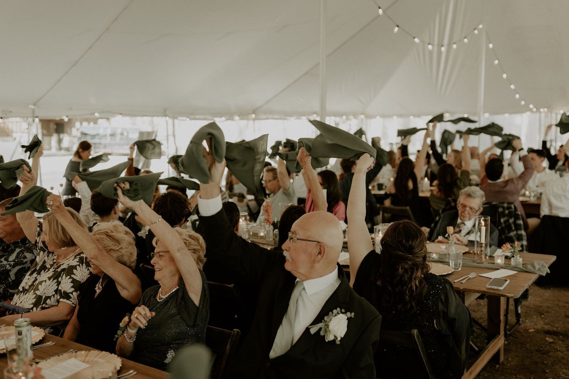 Tent wedding reception dance floor at Camp Elsewhere with guests waving napkins and Sound Sensations 
