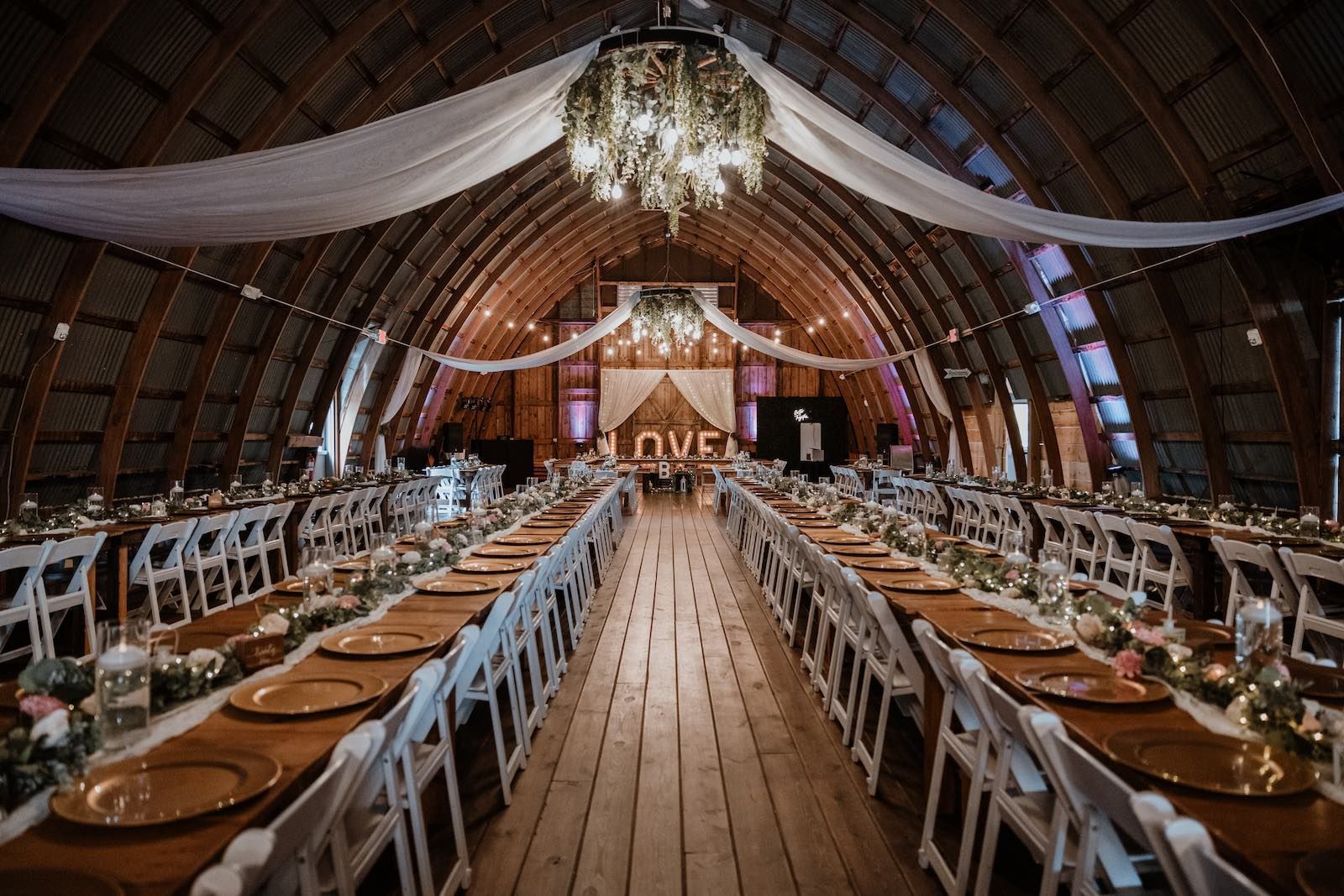 Barn wedding reception at Poplar Creek with diner tables set and Sound Sensations DJ booth in the background