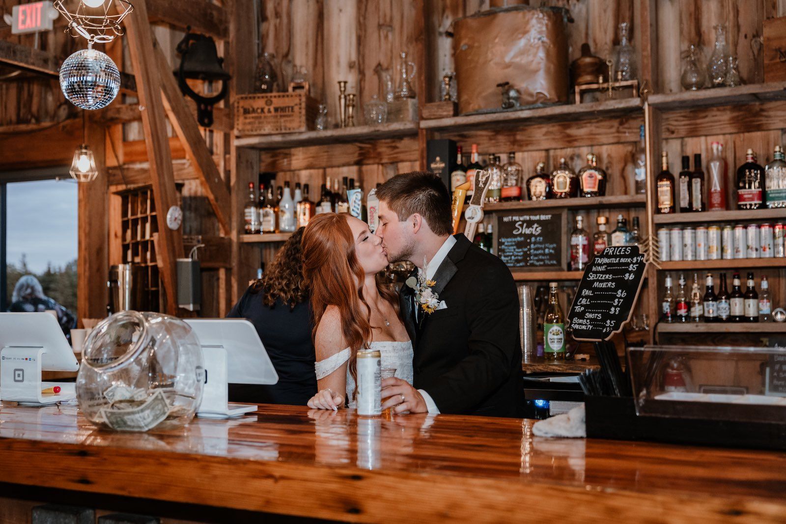 Barn wedding reception at Poplar Creek with bride and groom kissing behind venue bar,  Sound Sensations entertainment 