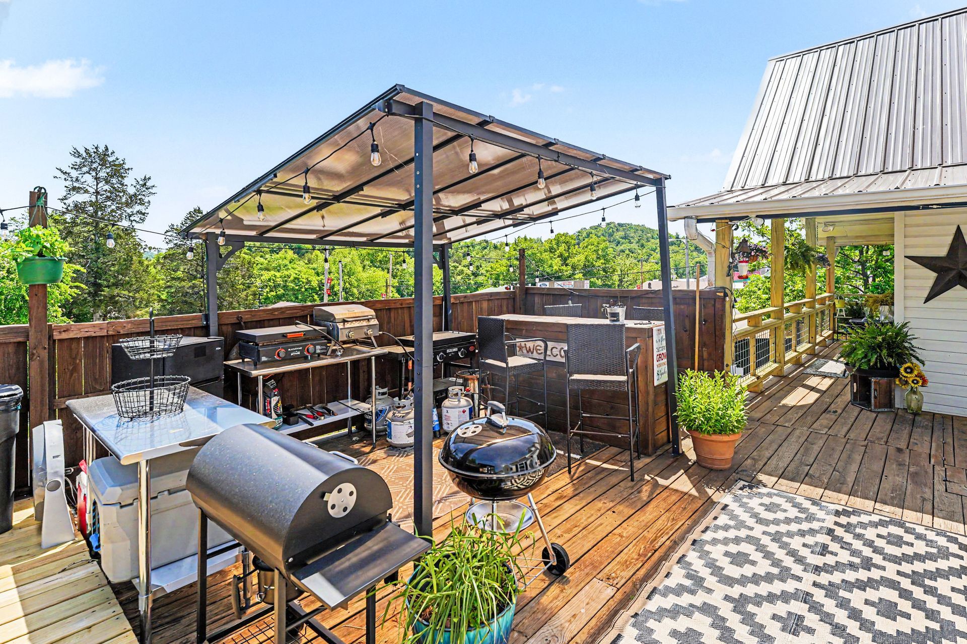 Backyard patio with grill, fire pit, and covered seating on a wooden deck beside a house