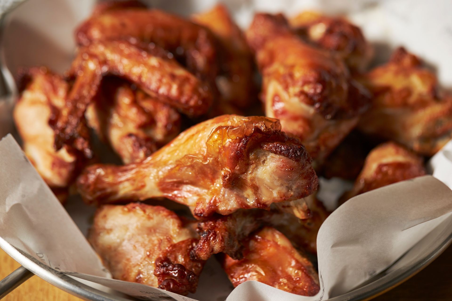 Tray of glazed roasted chicken wings in a paper-lined basket