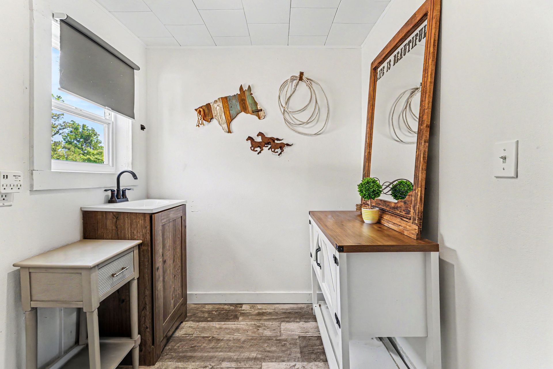 Small bright mudroom with sink, bench, rustic wall decor, and a white dresser with mirror.