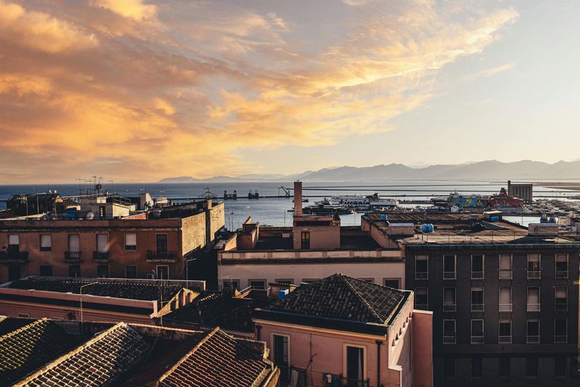 Aerial view of Izmir, Turkey at dusk, featuring waterfront with boats and a prominent historical building.