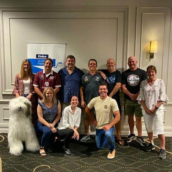 team posing for photo with dulux dog