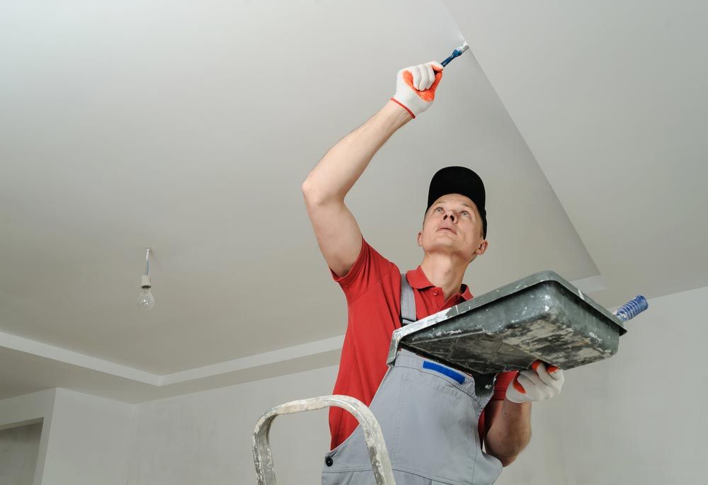 Man Painting The Ceiling With White