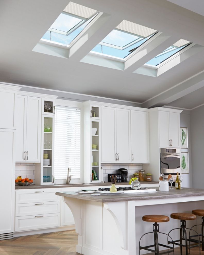 A minimalist bathroom with a black stone wall, a central black bathtub, skylights, and a white vanity with a mirror.
