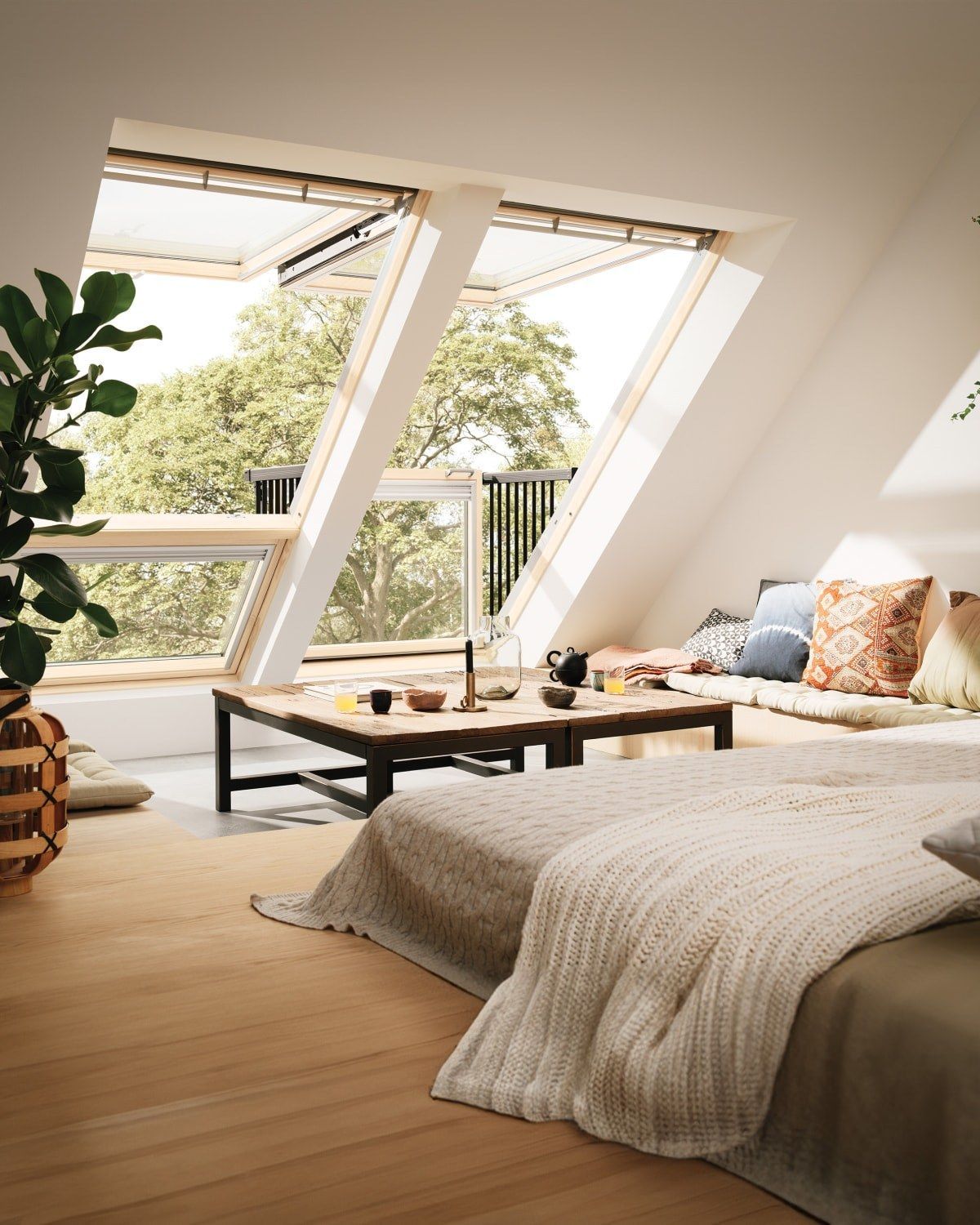 A bright, open-plan living and dining area featuring skylights, glass doors leading to a garden, and a blue sofa.