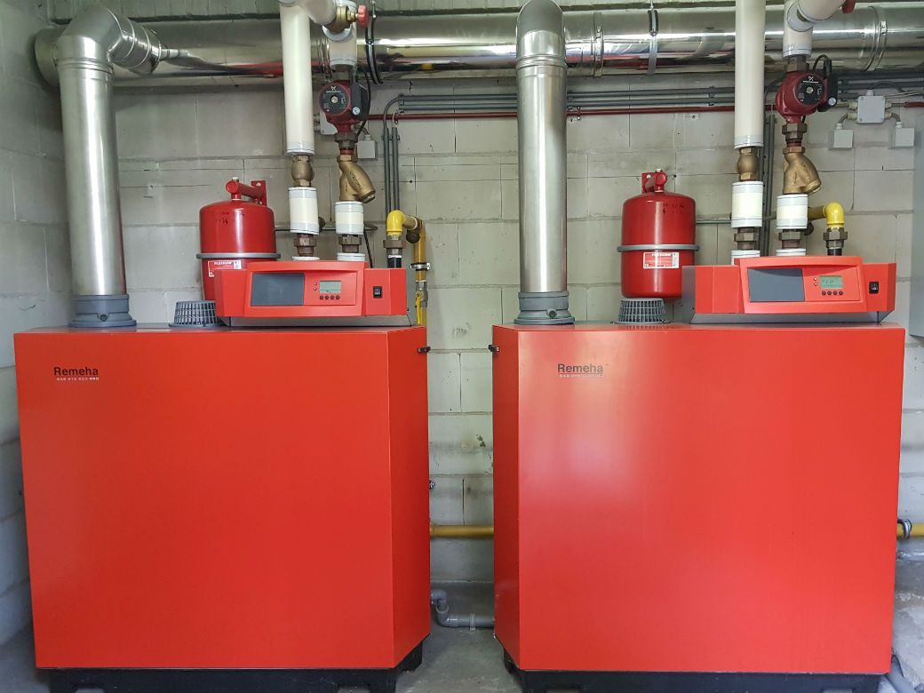 Twee rode boilers staan naast elkaar in een kamer.