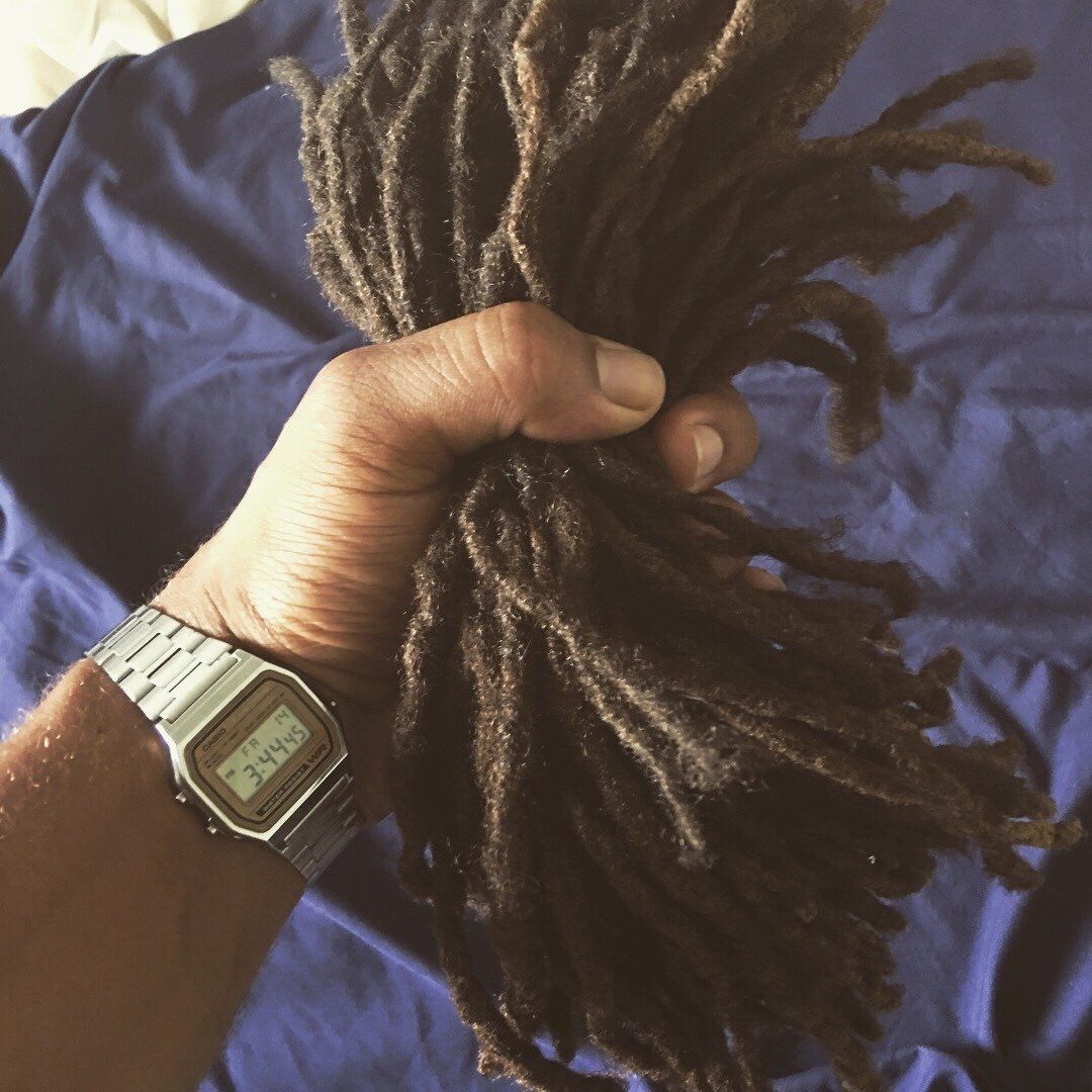 A person wearing a watch is holding a bunch of dreadlocks