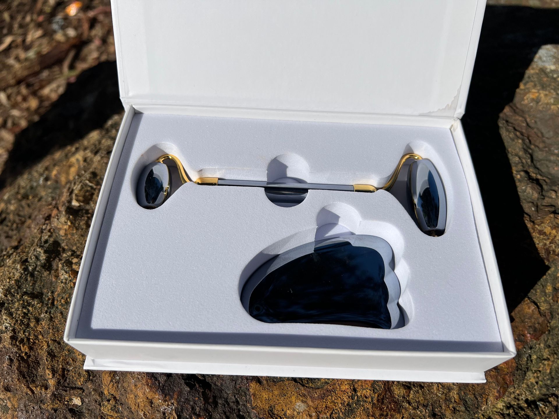 A facial roller and gua sha tool are sitting on top of a box.