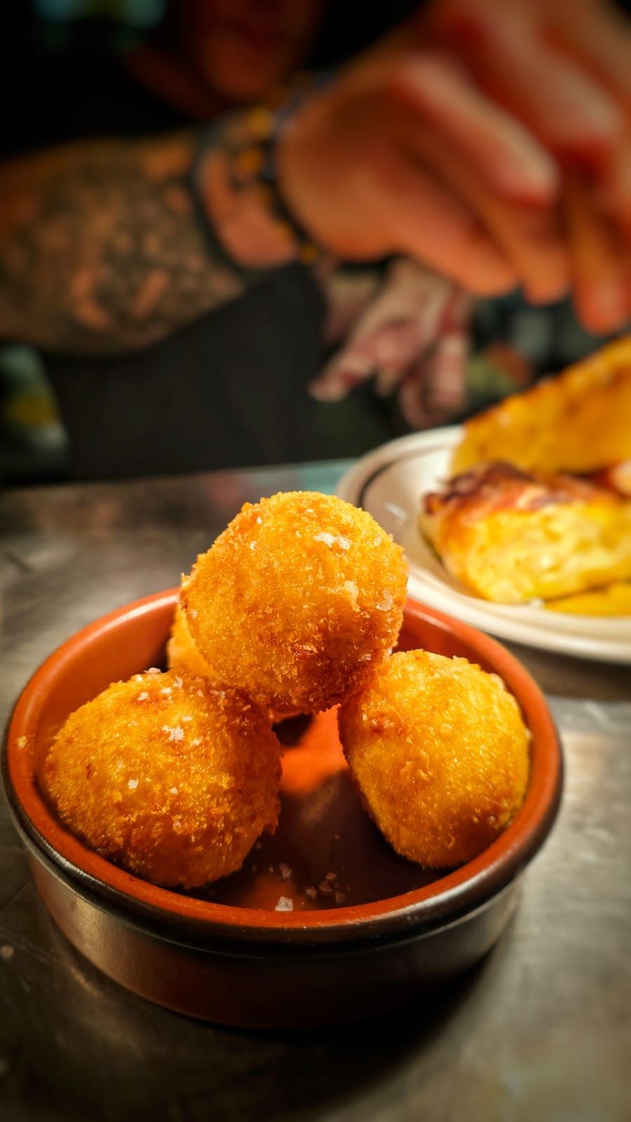 A bowl of fried food is sitting on a table next to a plate of food.