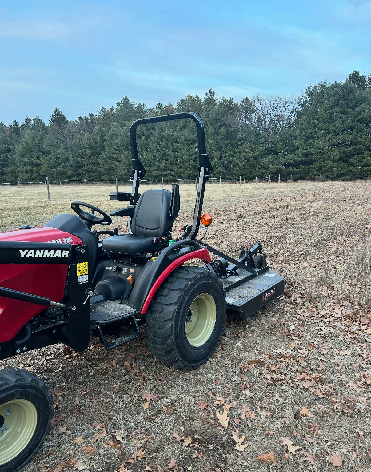 Red and black Yanmar tractor with a mower attachment on a field.
