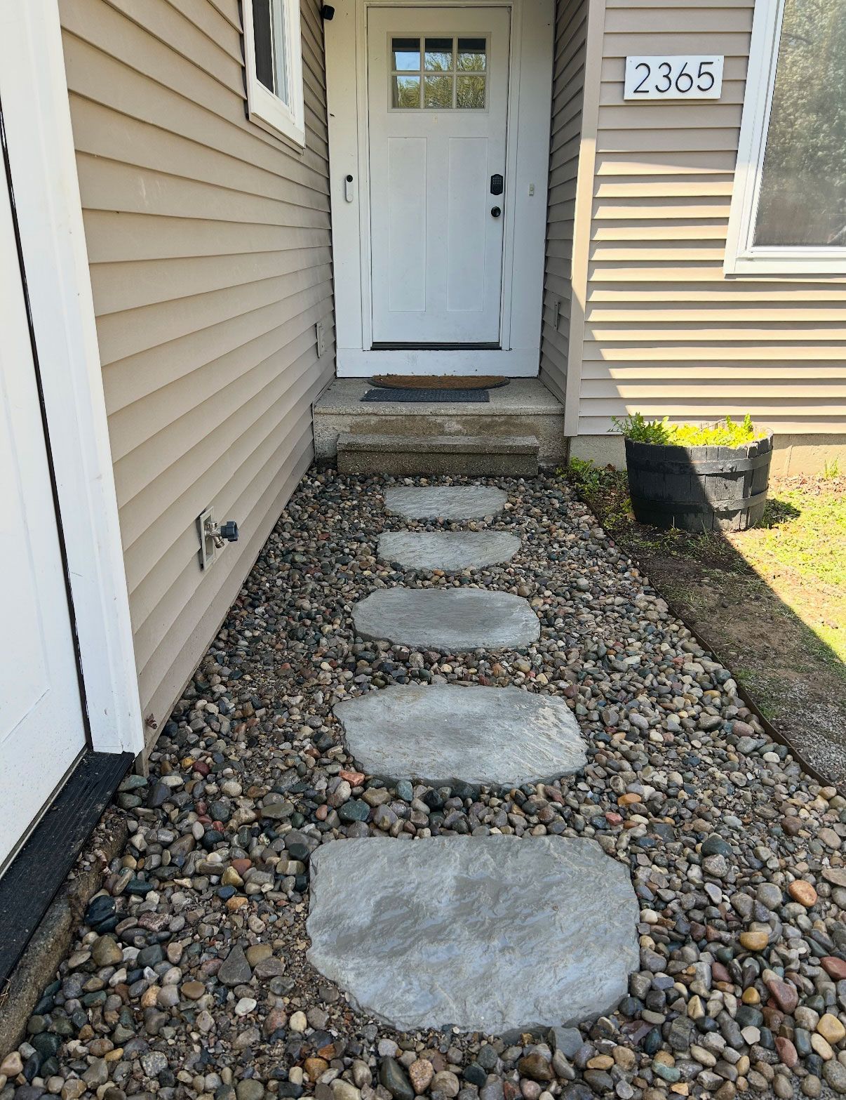 Pathway of stone steps leading to a white door with address 2365. Gravel ground.