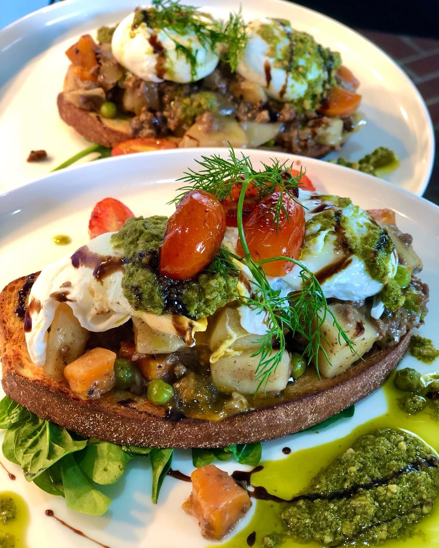 A Two Open-faced Sandwiches With Poached Eggs, Pesto, and Roasted Vegetables on White Plates — Flour in Yeppoon, QLD