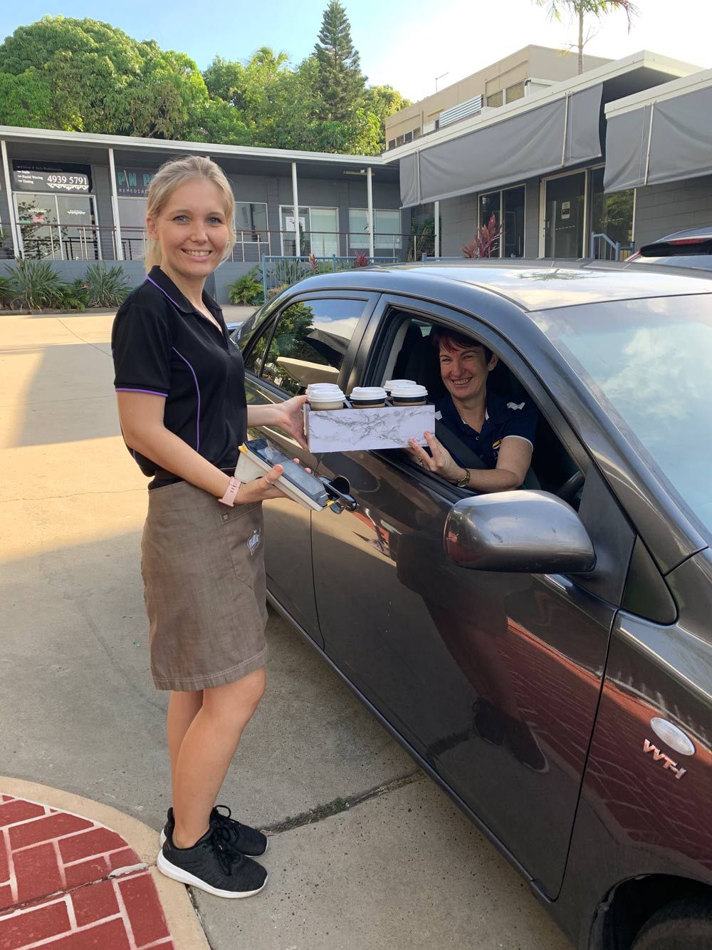 A Woman Handing a Bag of Food to Another Woman in a Car at a Restaurant for Curbside Pickup — Flour in Yeppoon, QLD