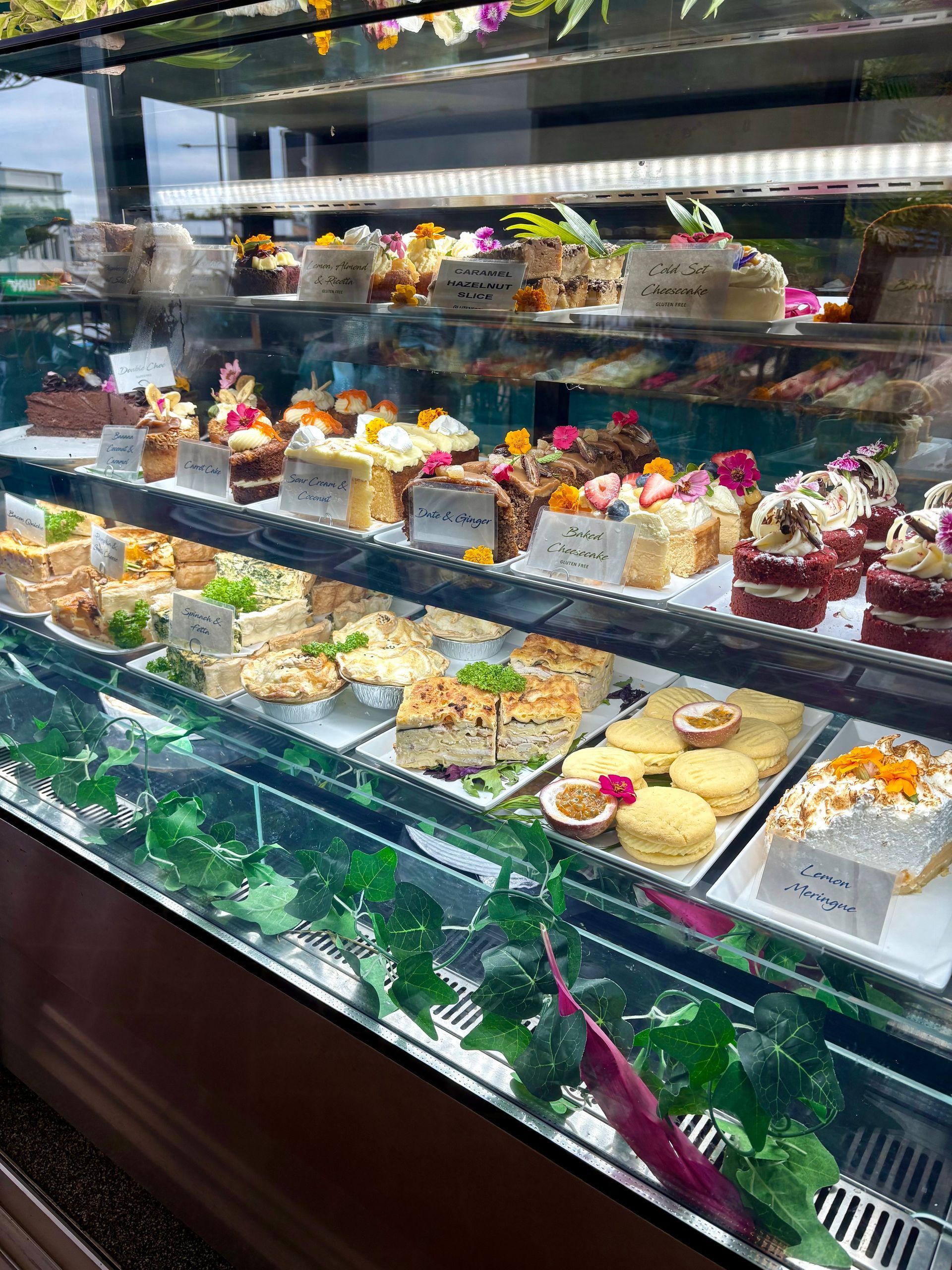 A Display Case Filled With Various Cakes and Baked Goods in a Cafe Setting — Flour in Yeppoon, QLD