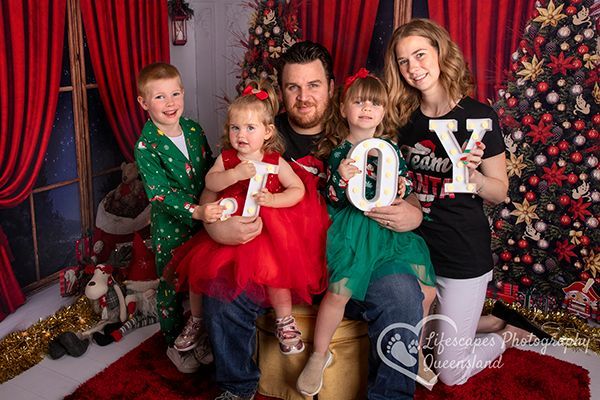 A family is posing for a picture in front of a christmas tree.