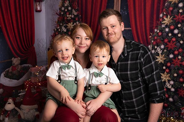 A family is posing for a picture in front of a christmas tree.