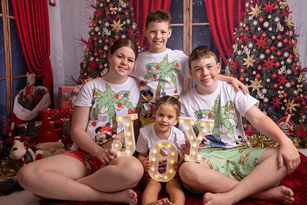 A family is posing for a picture in front of a christmas tree.