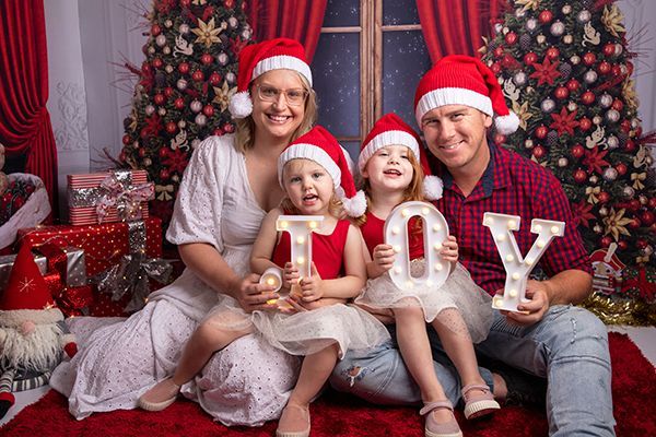 A family is posing for a picture in front of a christmas tree.