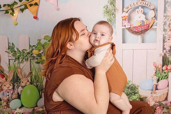 A woman is holding a baby and kissing it on the cheek.