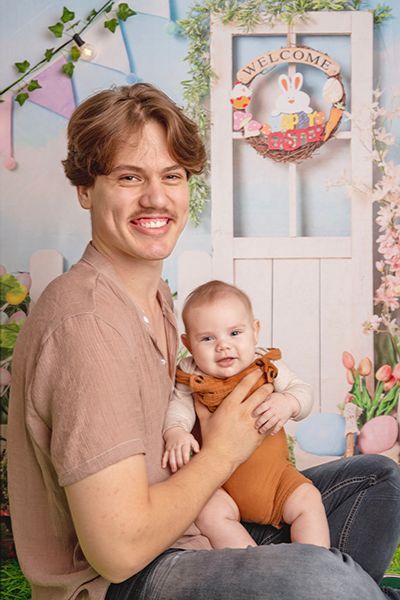 A man is holding a baby in his lap in front of a door.