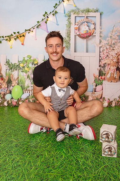 A man is sitting on the grass with a baby in his lap.