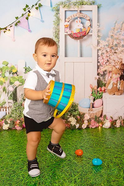 A little boy is standing on the grass holding a bucket.
