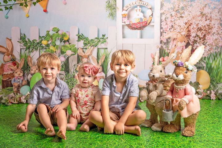 A group of children are sitting on the grass with easter bunny figurines.