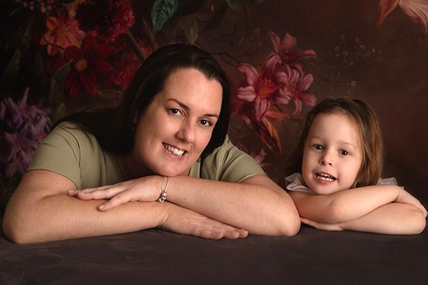 A woman and a little girl are posing for a picture.