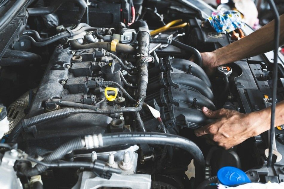 A Person is Working on the Engine of a Car — Autochange Mechanical Repairs & Tyres in Bellambi, NSW