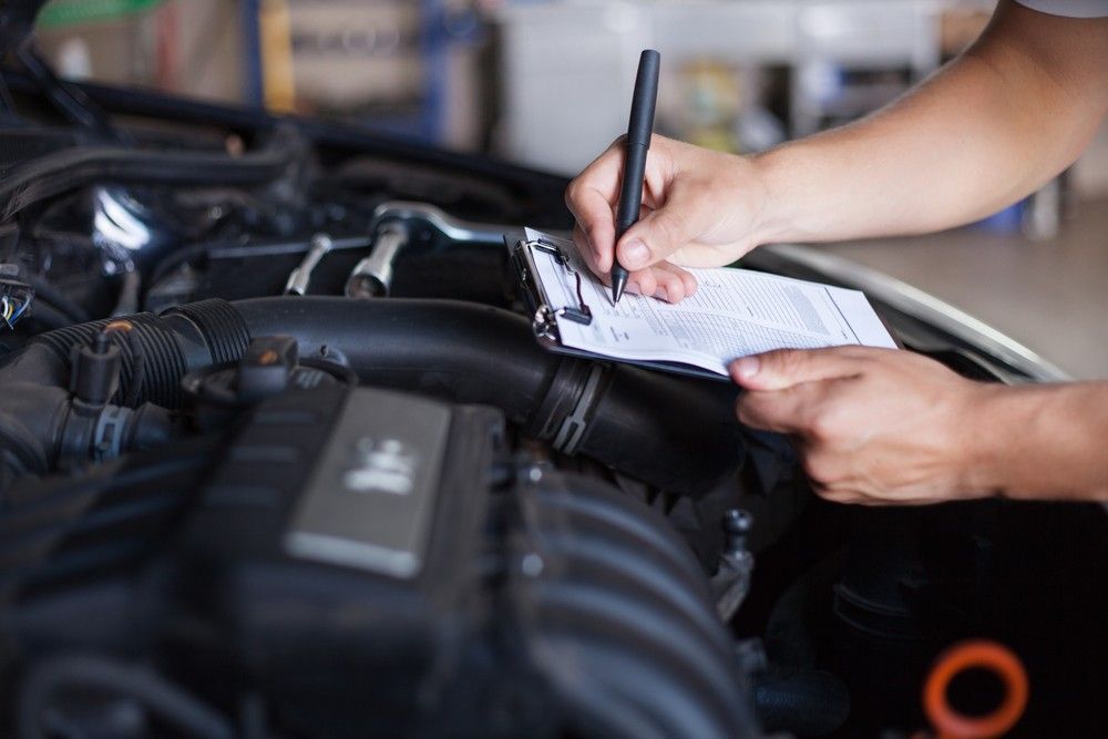 A Person is Writing on a Clipboard Under the Hood of a Car — Autochange Mechanical Repairs & Tyres in Bellambi, NSW