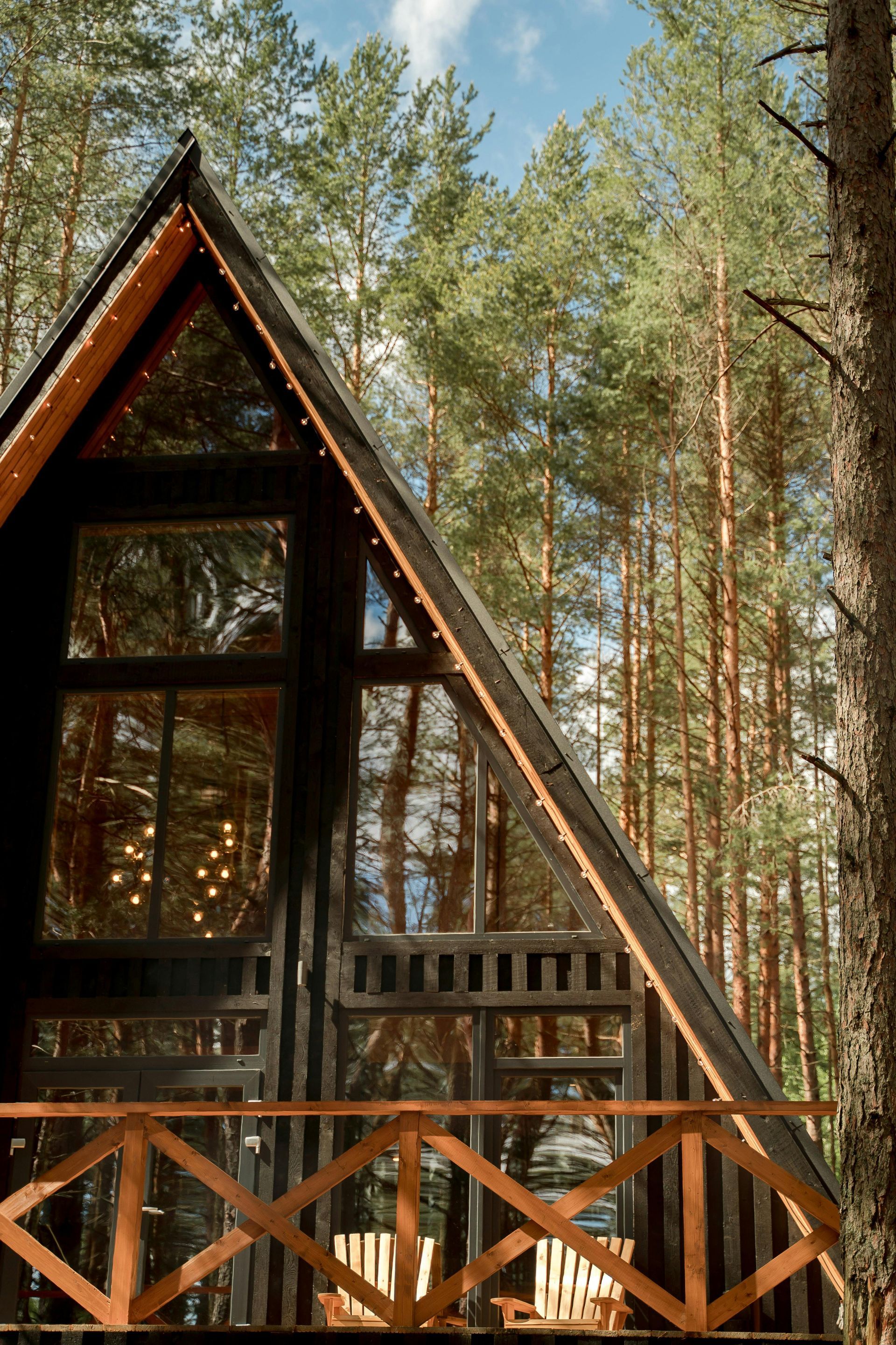 A small a frame house in the middle of a forest with a balcony.