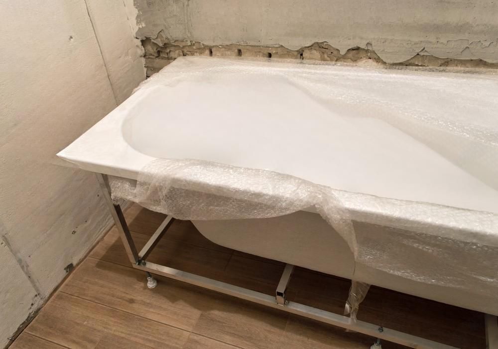 a white bathtub is sitting on top of a wooden floor in a bathroom .
