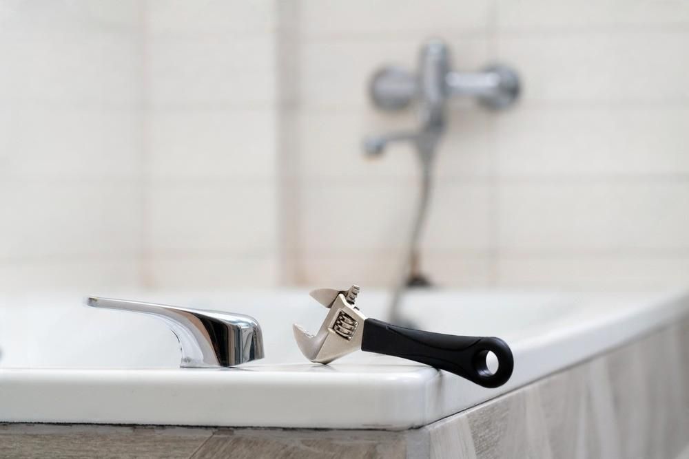 a wrench is sitting on the edge of a bathtub .