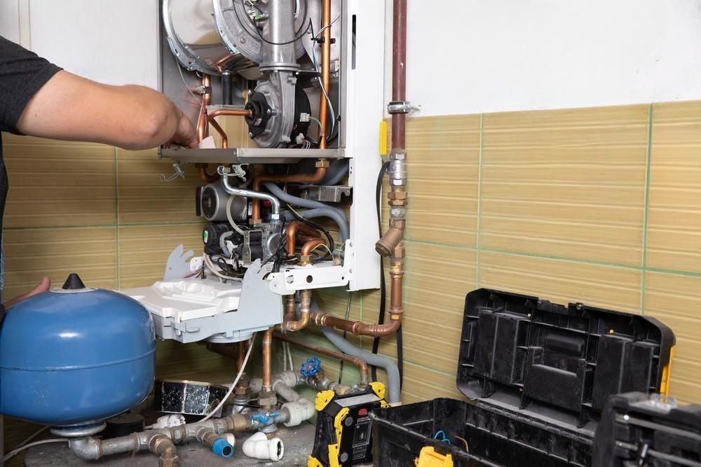 a man is working on a boiler in a bathroom .