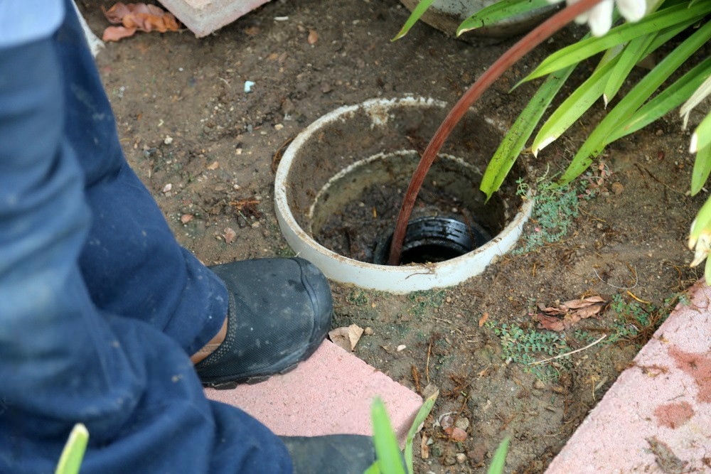 a person is working on a drain in the ground .