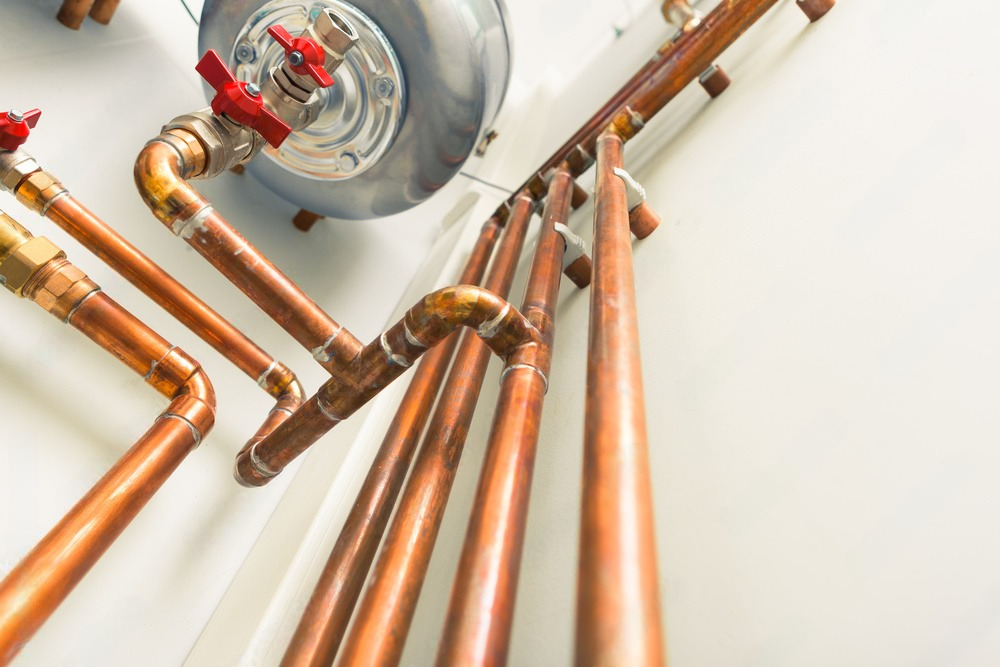 a row of copper pipes connected to a water heater on a wall .