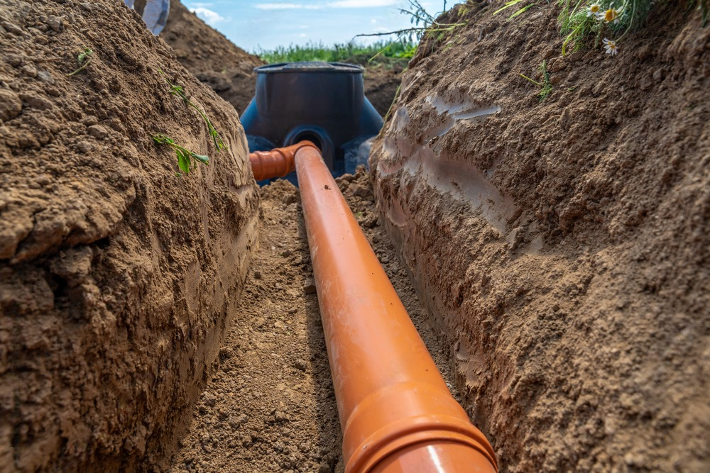 a pipe is being installed in a trench in the dirt .
