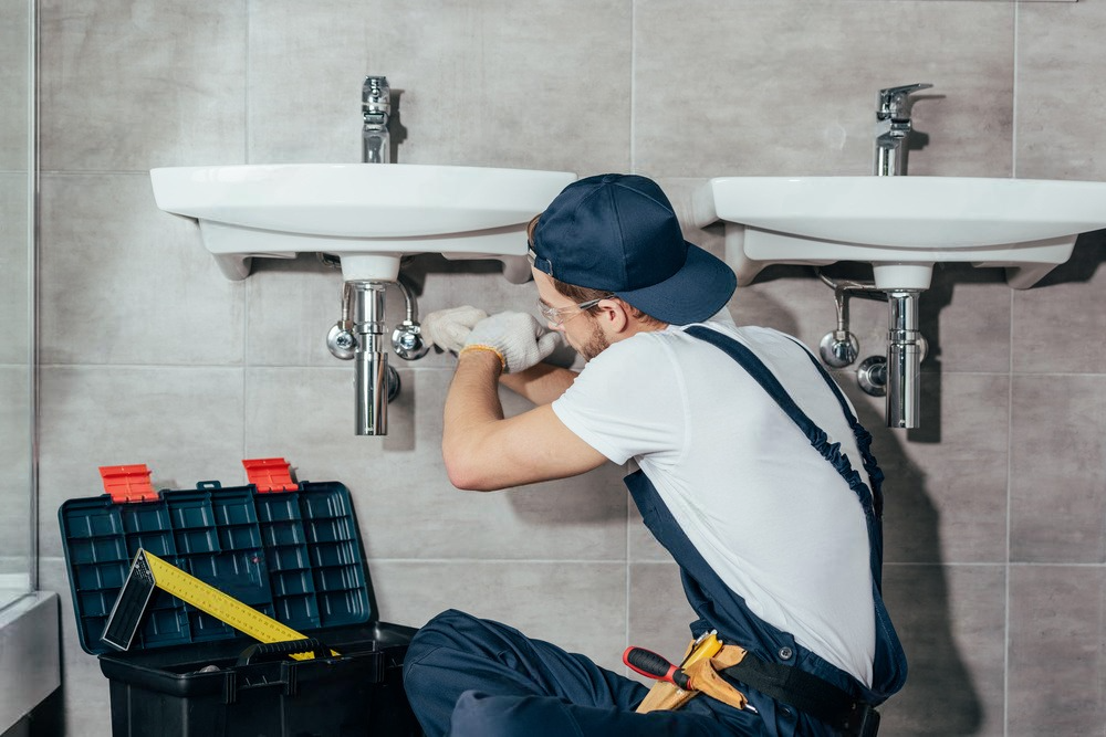 Focused middle-aged man repairing a burst pipe in a plumbing project.
