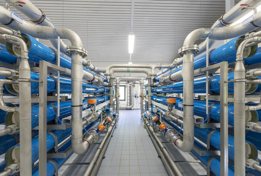 a hallway filled with lots of blue pipes in a factory .