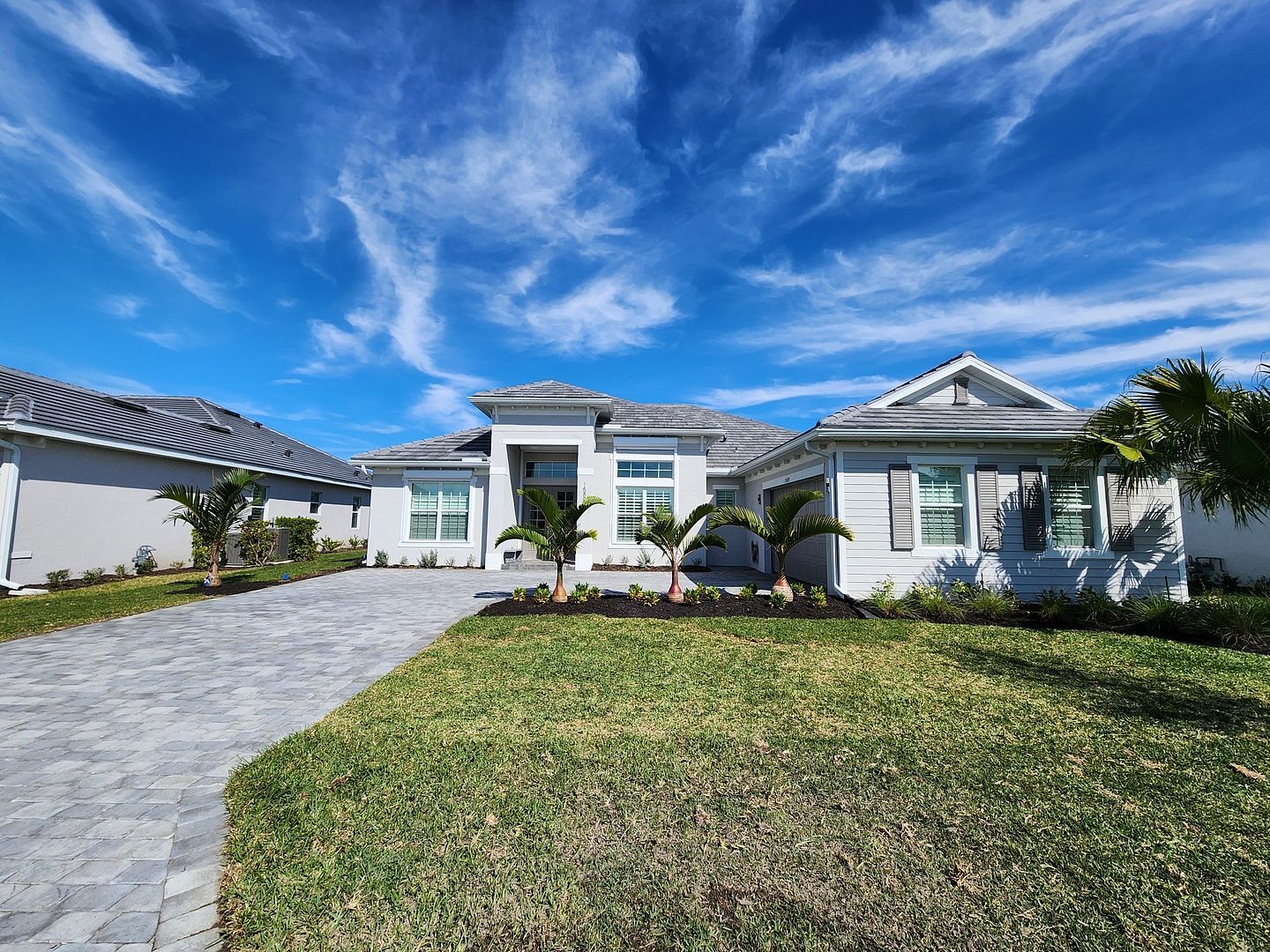 A large white house with a lush green lawn and a driveway leading to it.