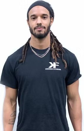 A man with dreadlocks is wearing a black t-shirt and a headband.