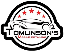 Logo for Tomlinson's Mobile Detailing, features a car silhouette, red stars, and text in a black and white circular design.